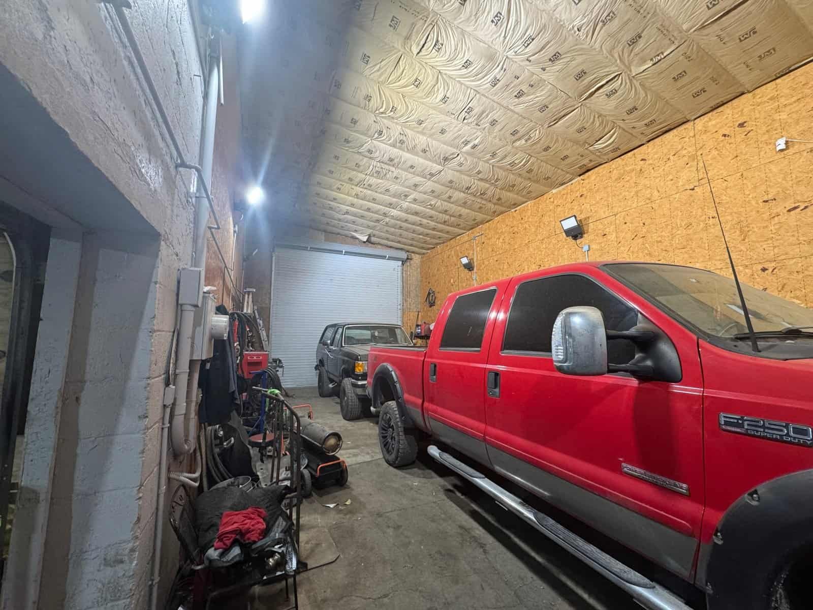 Heavy-duty red pickup truck parked inside a garage with unfinished walls and ceiling, showcasing the rugged Cordura RE fabric used for vehicle upholstery and protective coverings.