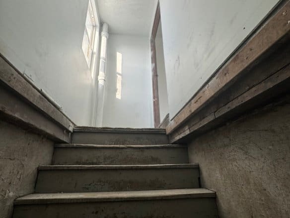 Interior view of a staircase with concrete steps and unfinished walls, showcasing the durability of Cordura RE fabric used in construction or renovation projects.