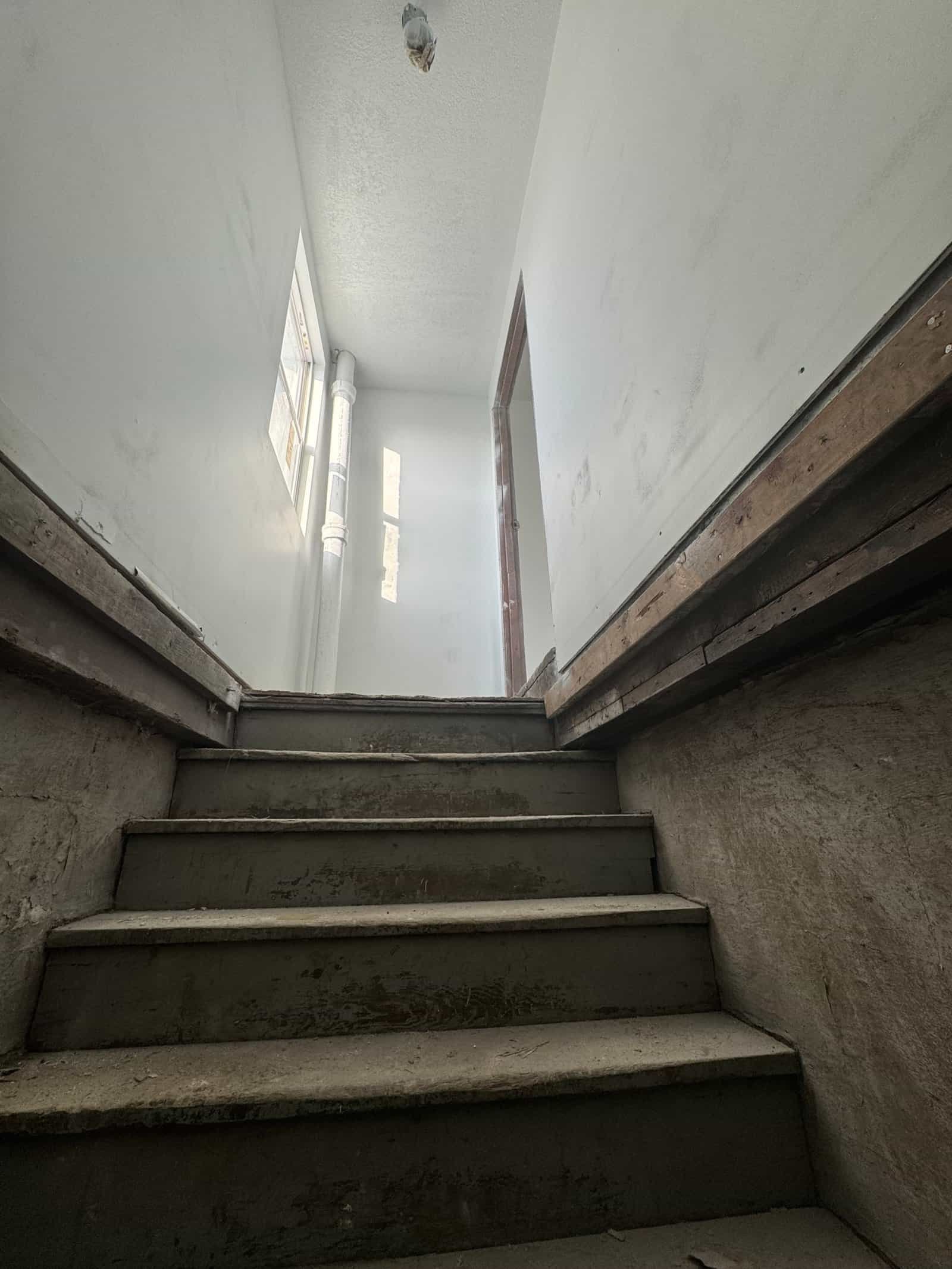 Interior view of a staircase with concrete steps and unfinished walls, showcasing the durability of Cordura RE fabric used in construction or renovation projects.