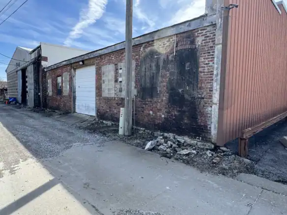 Image of an industrial building with brick walls and a large garage door, showcasing durable construction materials like Cordura RE fabric for industrial applications.