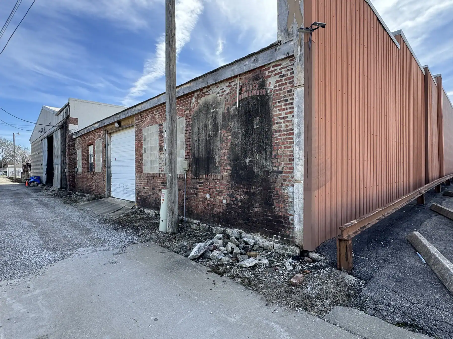 Close-up of a weathered brick wall with a red metal fence, showcasing durable industrial materials like Cordura RE fabric for construction and outdoor applications.