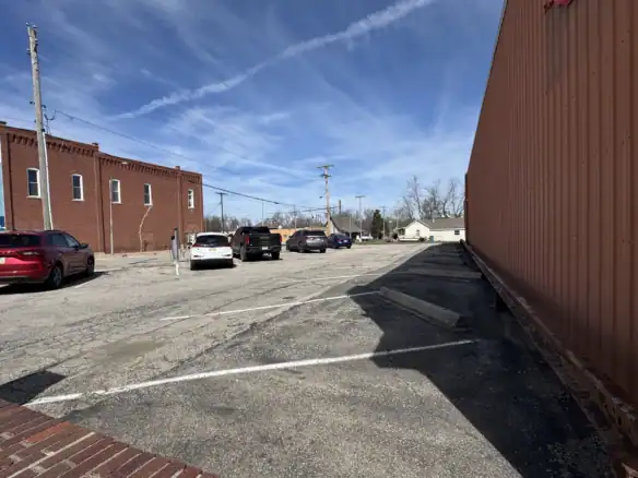 Outdoor storage lot with Cordura RE fabric-covered building and parked cars under a blue sky.