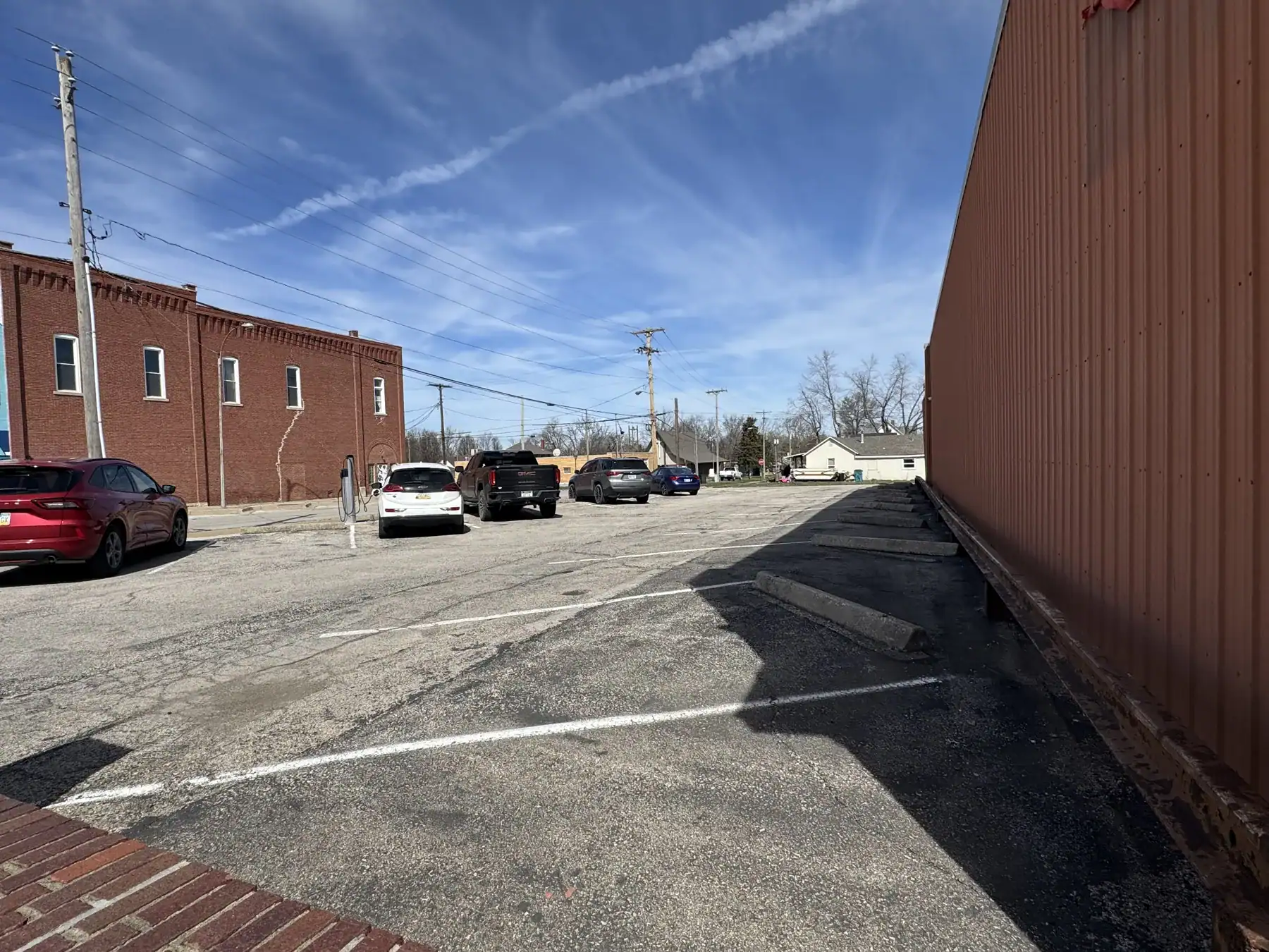 Outdoor storage lot with Cordura RE fabric-covered building and parked cars under a blue sky.